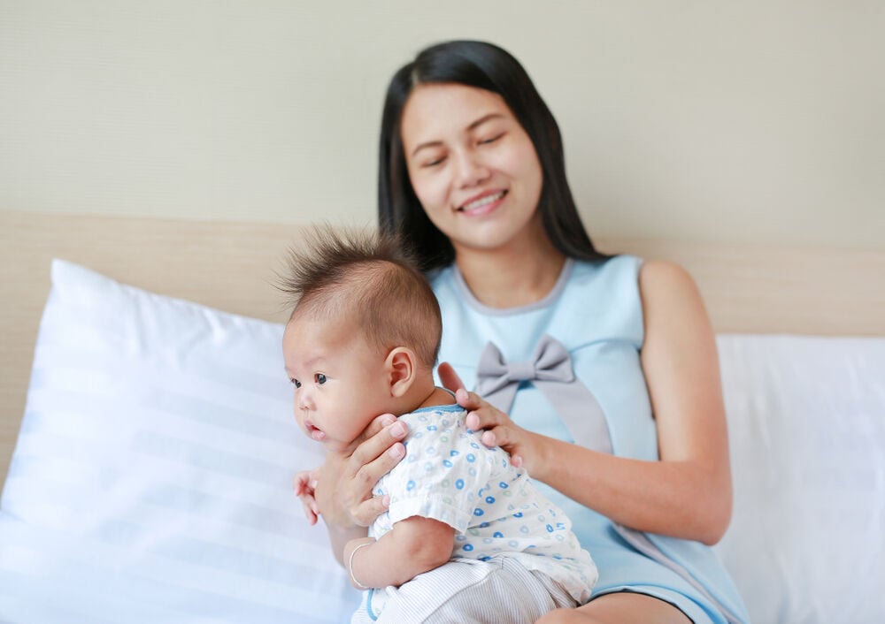 A mom burping her baby to stop baby hiccups after feeding A mom burping her baby to stop baby hiccups after feeding
