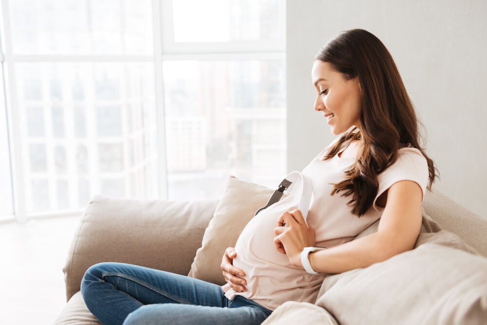 A woman holding earphones near her belly bump when a baby in the womb can hear A woman holding earphones near her belly bump when a baby in the womb can hear
