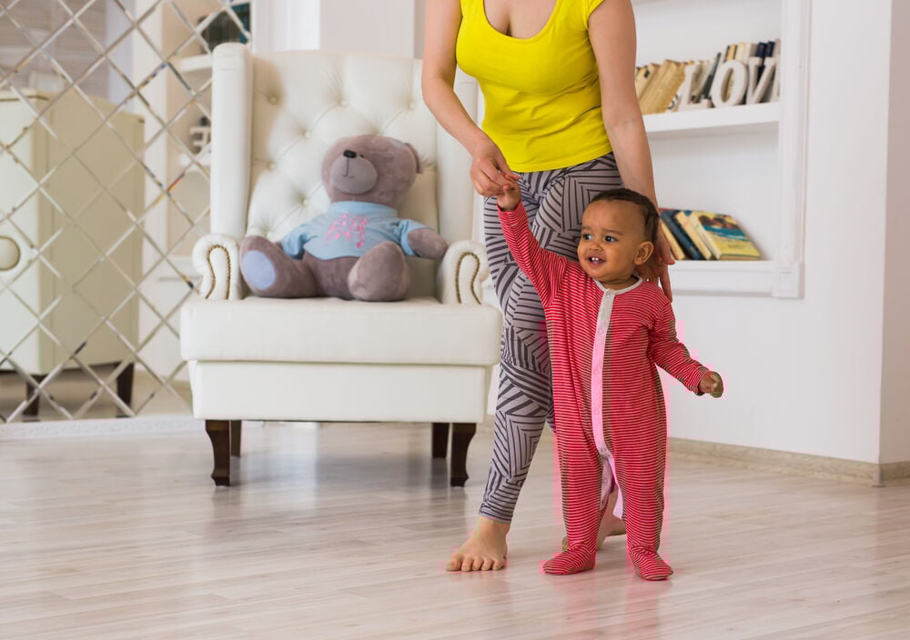 A mother helping her baby stand A mother helping her baby stand