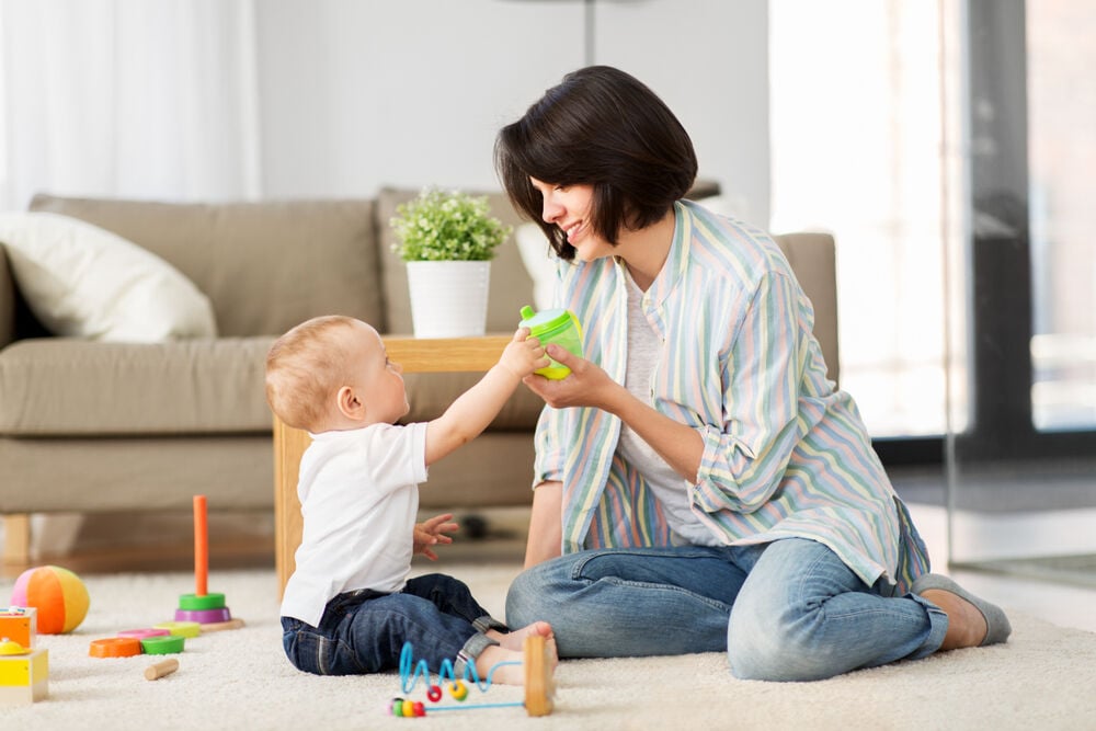 A mother giving her baby water in a sippy cup A mother giving her baby water in a sippy cup