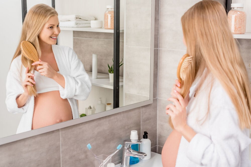 A pregnant woman brushes her hair A pregnant woman brushes her hair