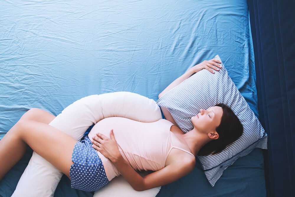 A woman sleeping while pregnant using a support pillow A woman sleeping while pregnant using a support pillow