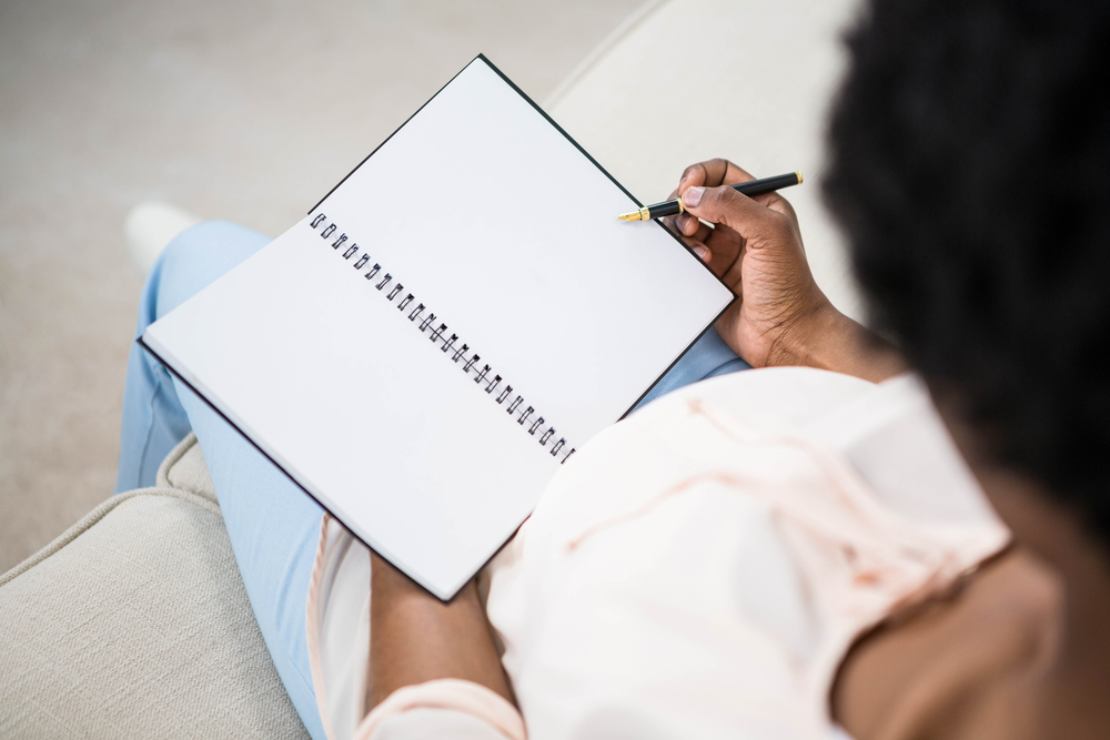 Pregnant woman holding notebook on couch Pregnant woman holding notebook on couch