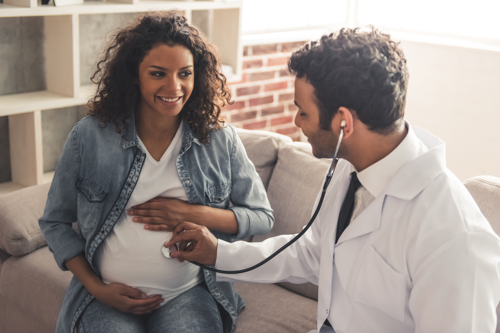 a doctor in a white coat is consulting a pregnant woman in his office a doctor in a white coat is consulting a pregnant woman in his office