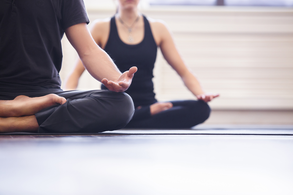 Young couple meditating together, sitting back to back doing free bleeding yoga Young couple meditating together, sitting back to back doing free bleeding yoga