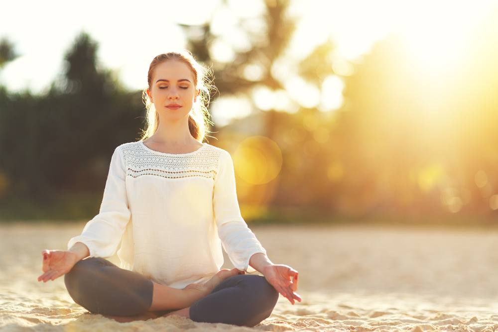 woman practices yoga and meditates in the lotus position on the beach woman practices yoga and meditates in the lotus position on the beach