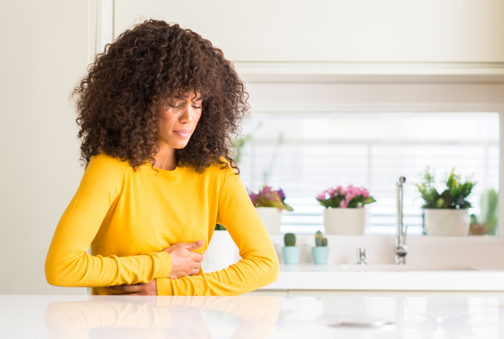 Woman in a yellow pullover feeling nausea Woman in a yellow pullover feeling nausea