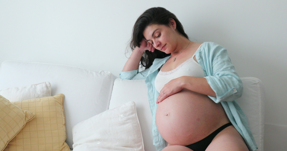 A pregnant woman rests on the couch