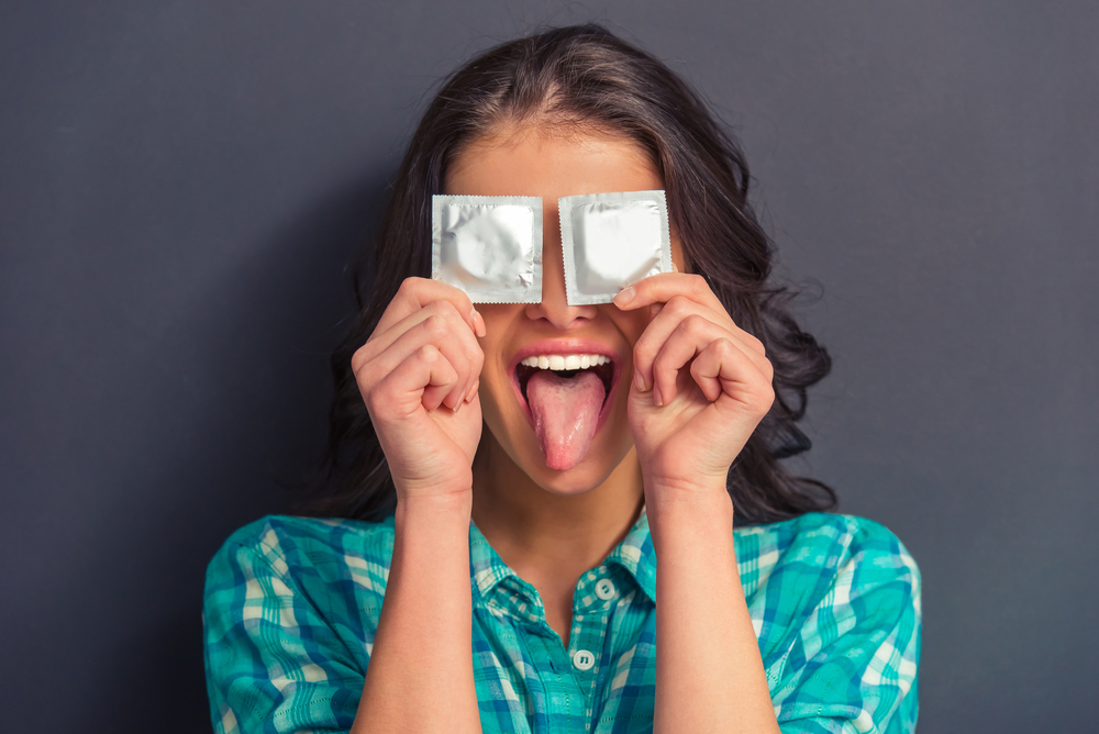 una mujer con dos preservativos para prevenir el embarazo una mujer con dos preservativos para prevenir el embarazo