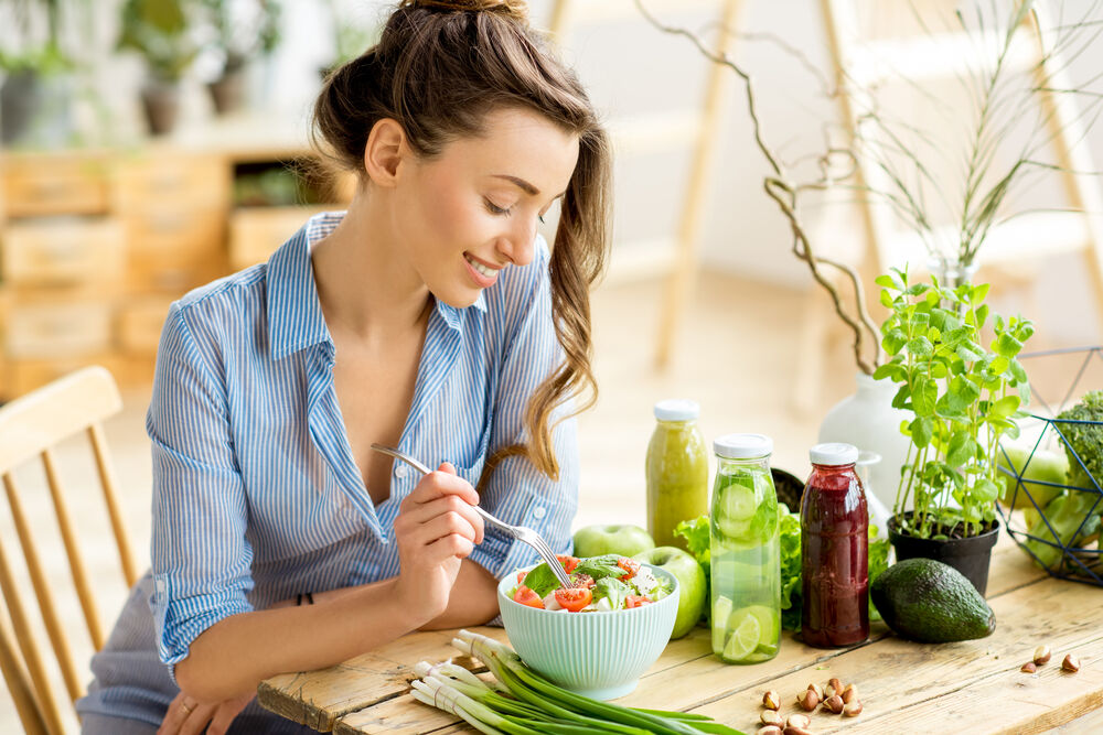  woman eating healthy salad to avoid hypothalamic amenorrhea