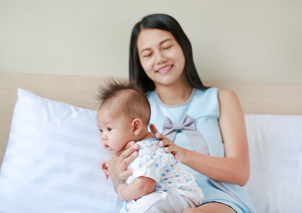 A mom burping her baby to stop baby hiccups after feeding