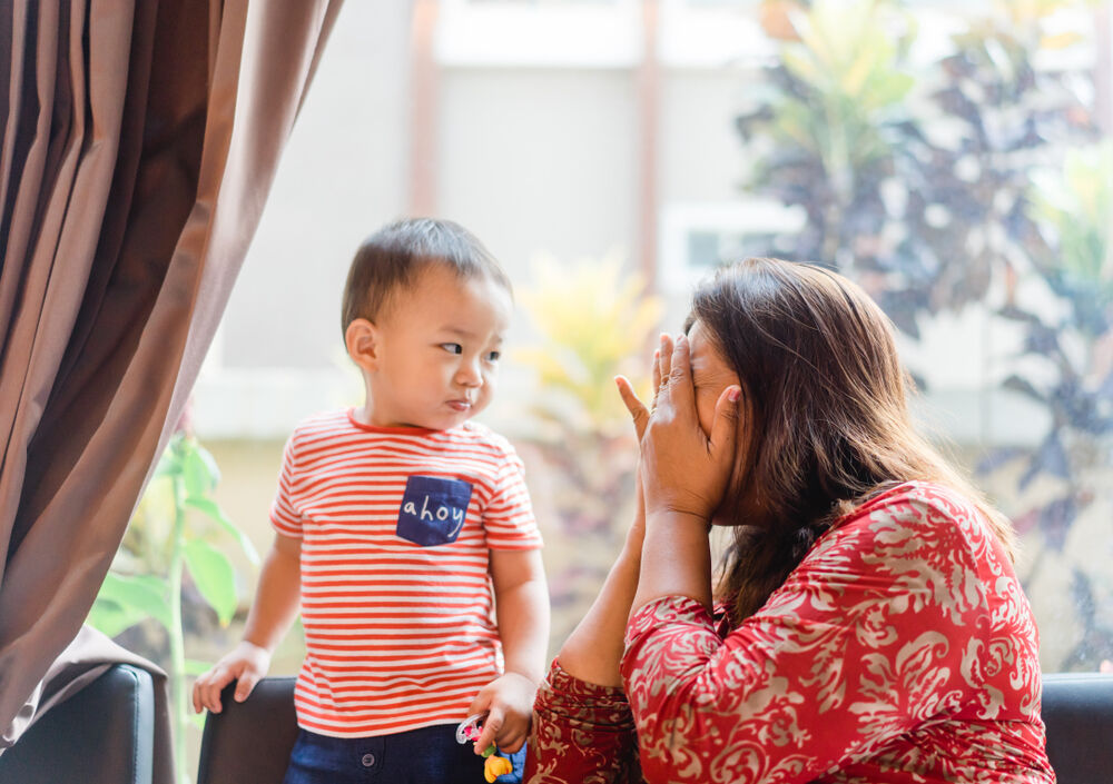 A mother playing peek-a-boo with her kid to help him deal with fears