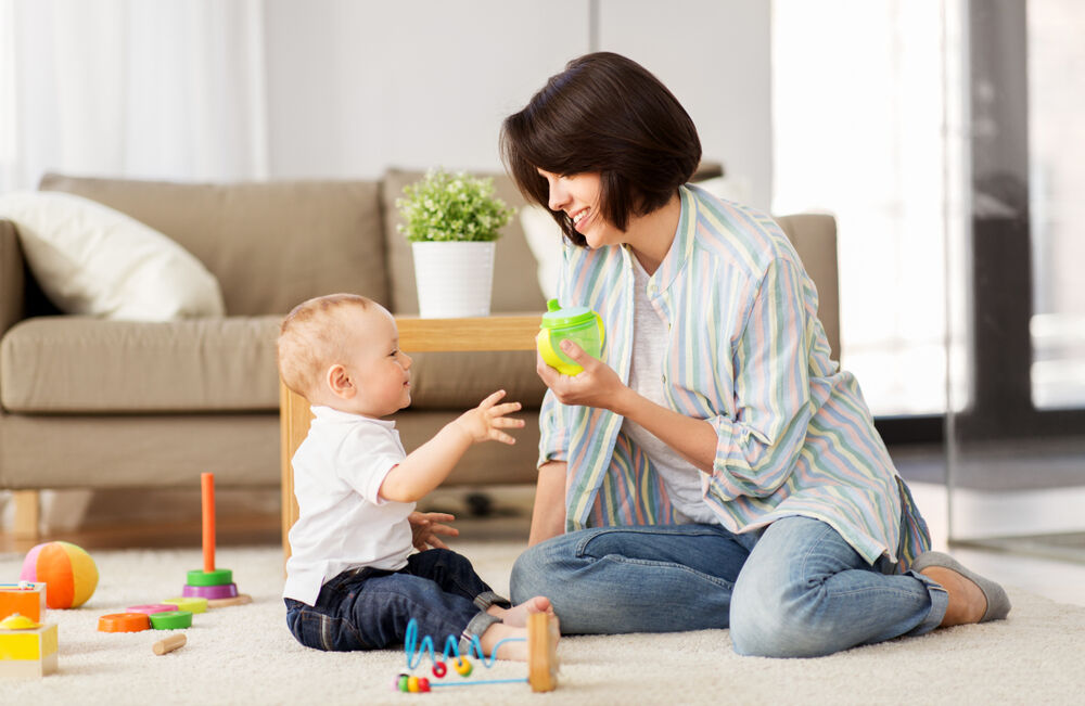 A woman gives her baby a sippy cup to wean the baby off the bottle