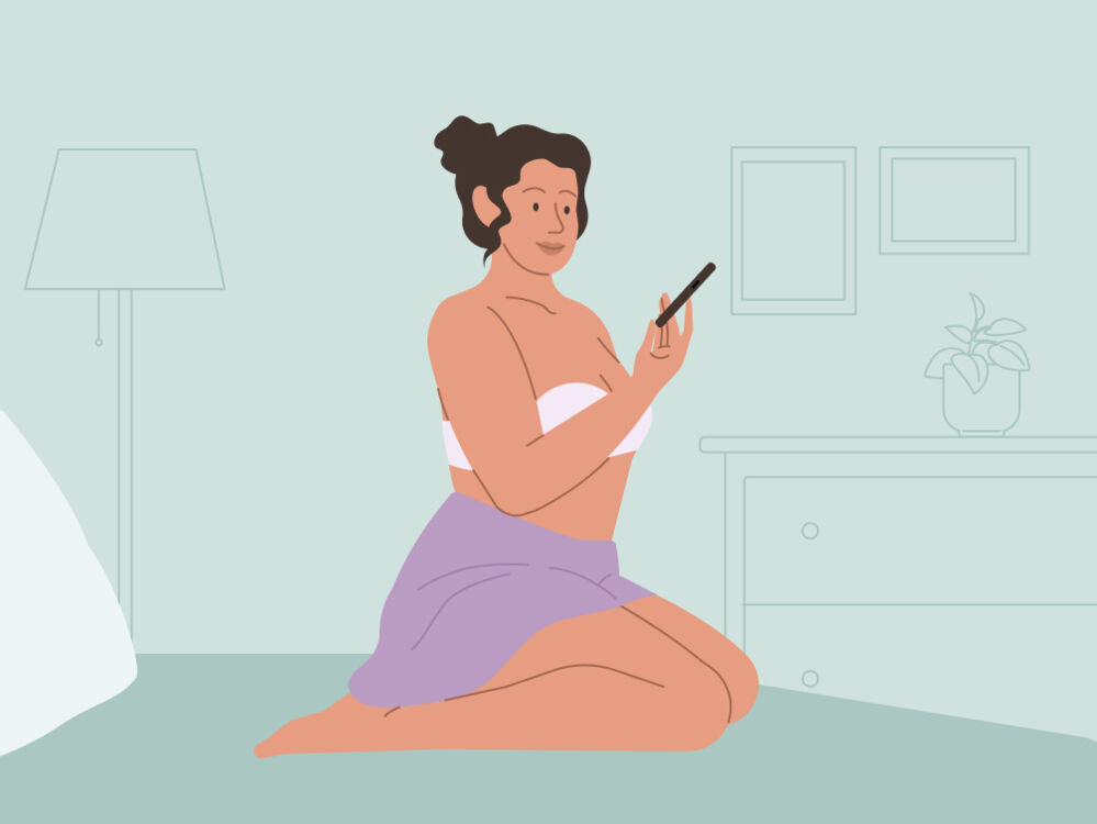A woman looking at her phone on the bed
