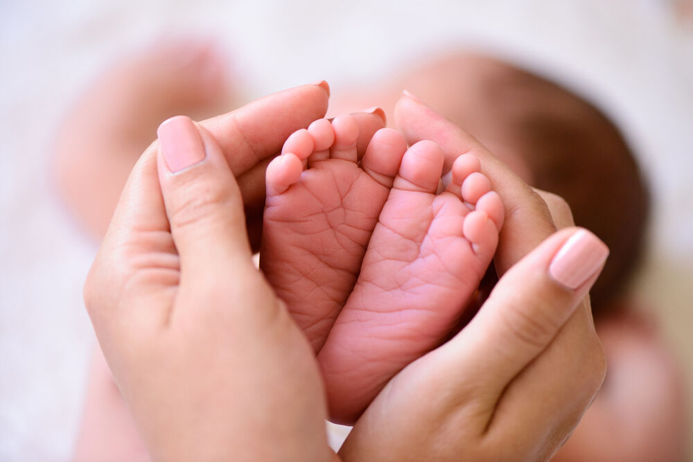 Mother holding tiny feet of a newborn baby