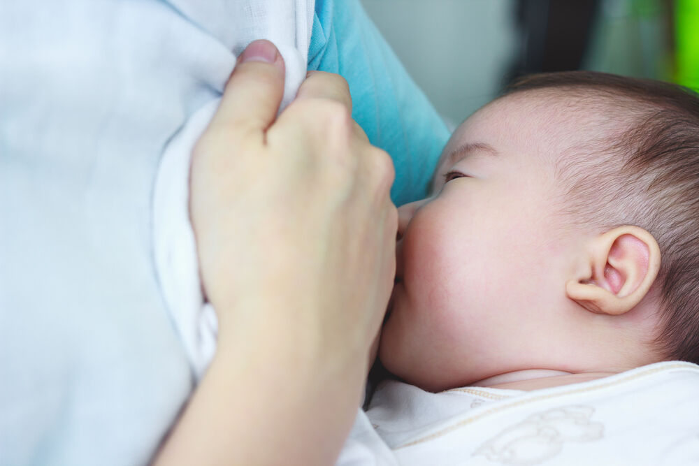 Mother breastfeeding her newborn baby with breast milk