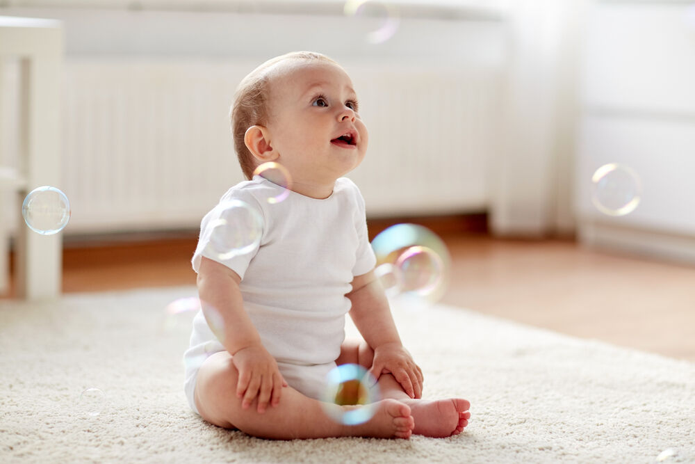 A 6-month-old baby playing with bubbles