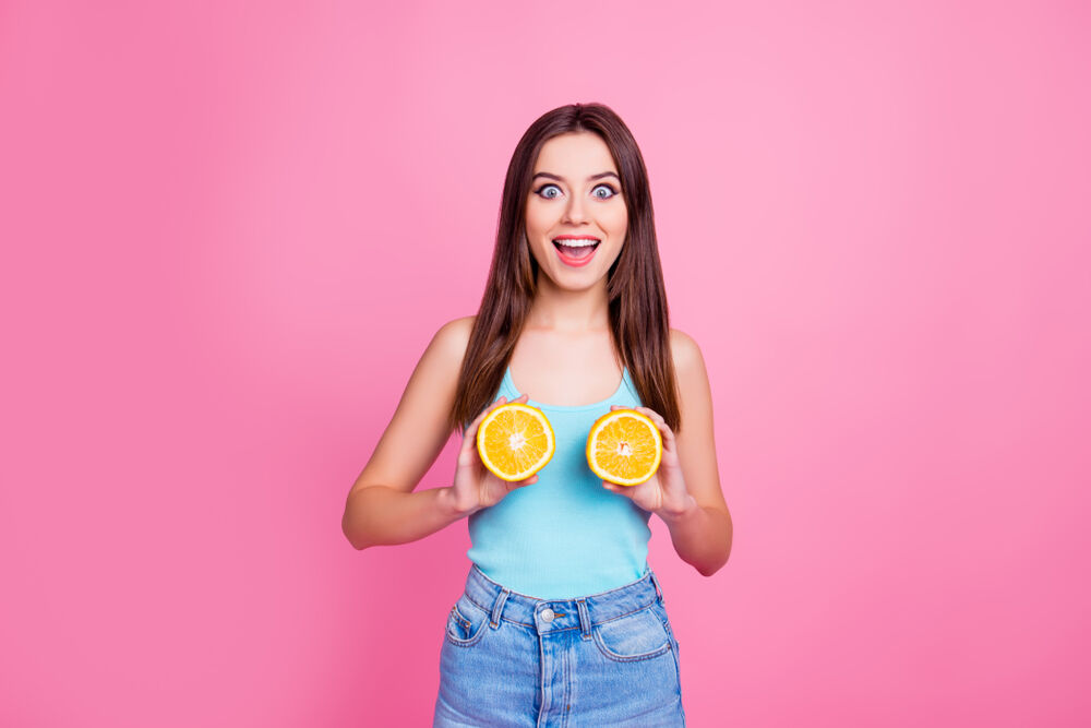 una niña con dos naranjas para simbolizar dolor de pechos