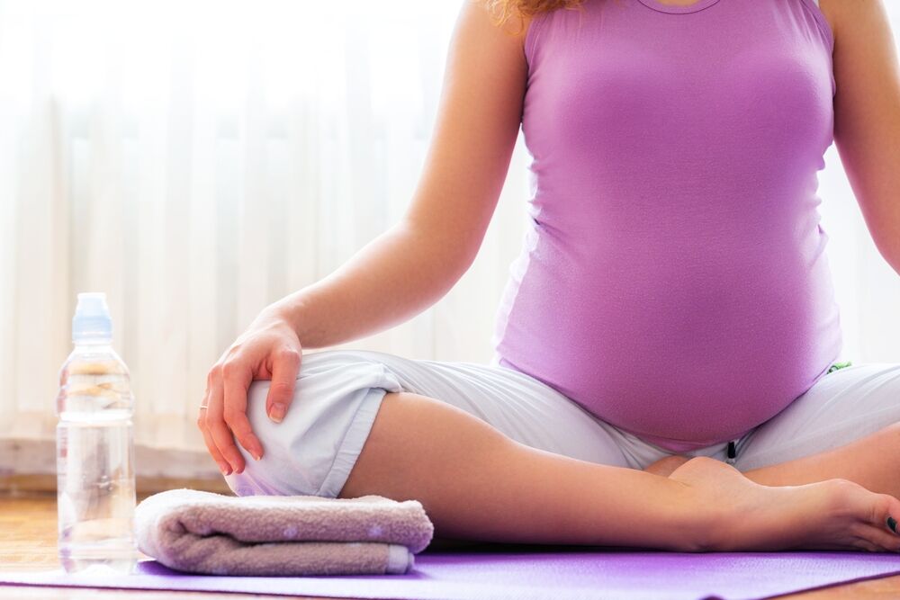 Young pregnant woman doing yoga at home