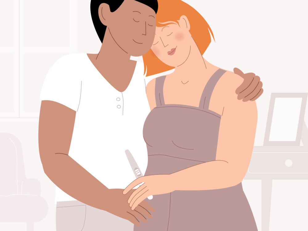 Two people hugging while holding a positive pregnancy test