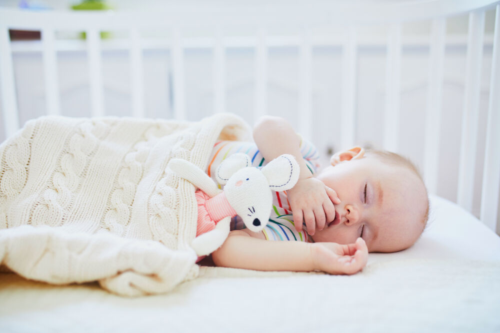 A baby sleeping under a baby blanket