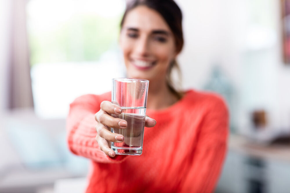 woman showing drinking glass with water