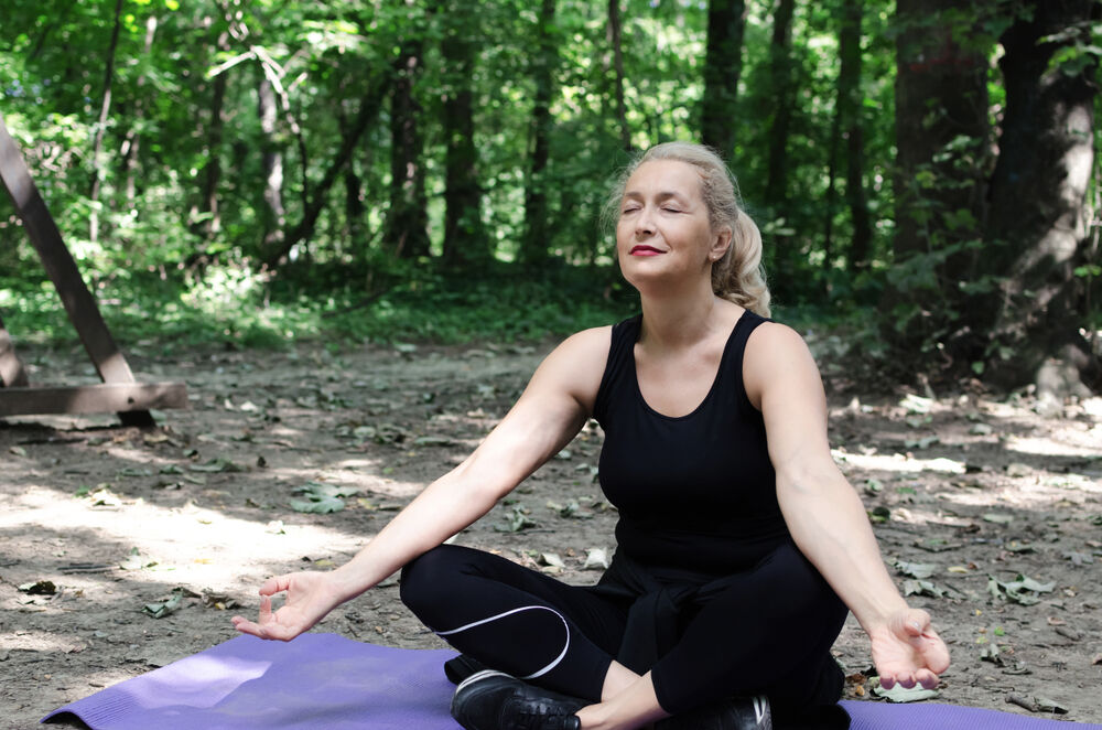 A woman is practicing yoga to treat headaches during menopause