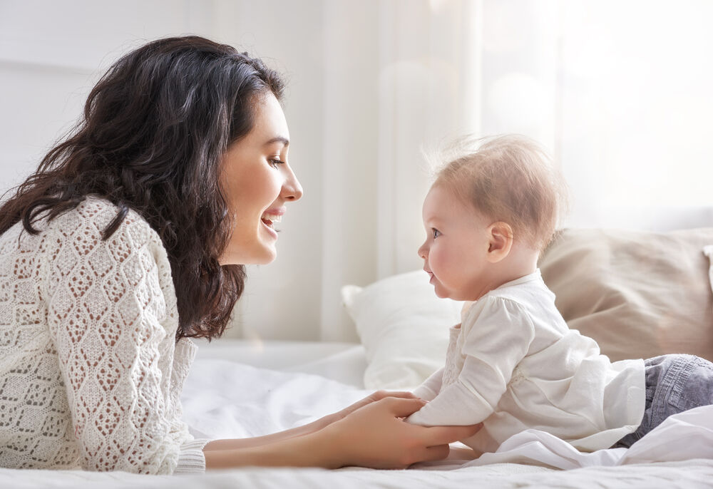 A mother with her  baby who is banging their head on the floor