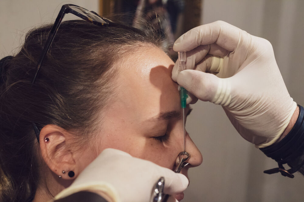 A young woman getting her nose pierced