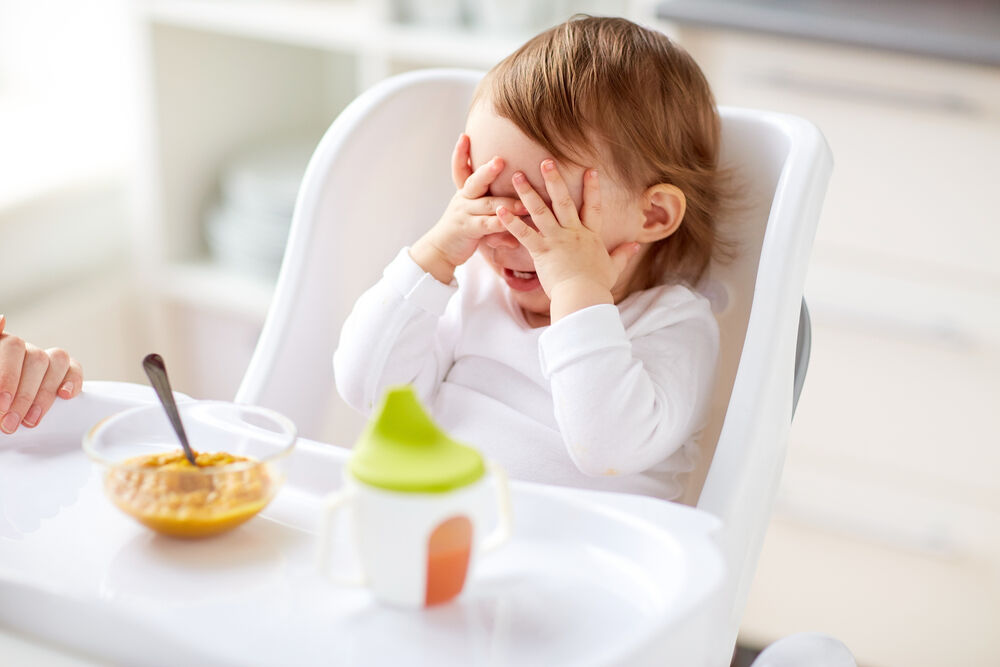 A woman trying to get her baby eating