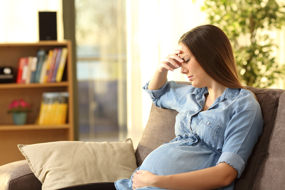 pregnant woman sitting on a couch in the living room at home