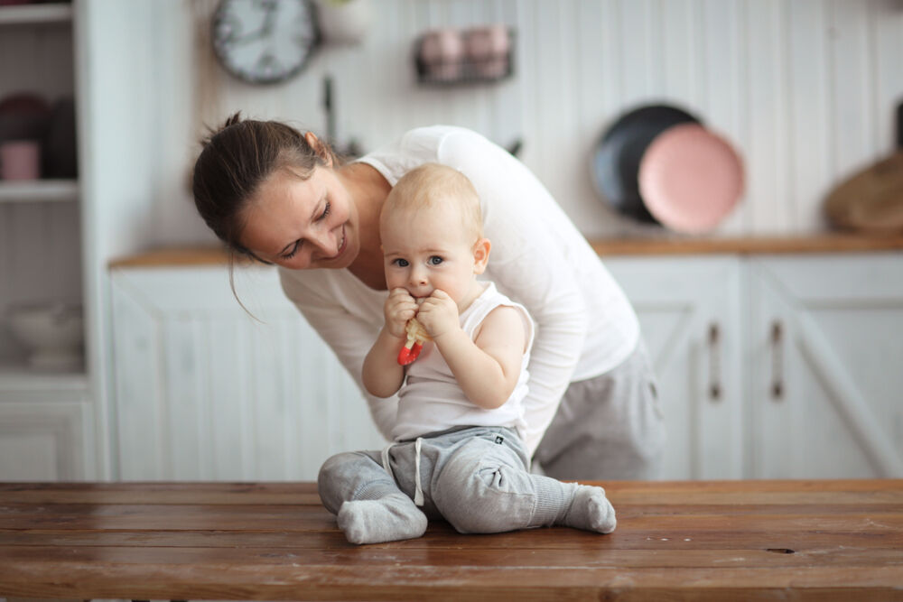 A woman gives her baby a teething toy to stop biting during breastfeeding 