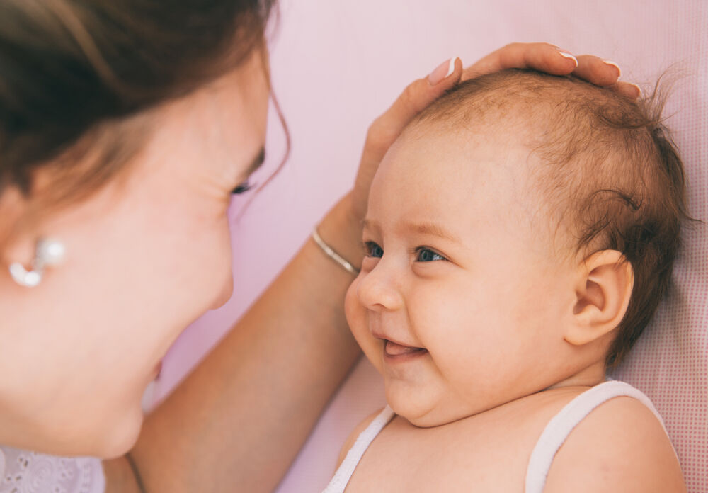 A woman trying to encourage a baby to smile