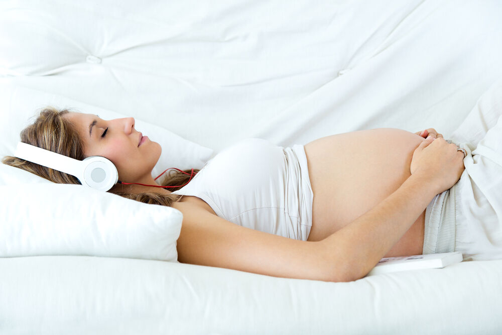 A woman is listening to the music to manage stress while she is pregnant