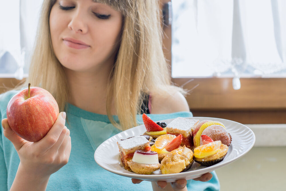 A woman holding a plate of foods to avoid during periods