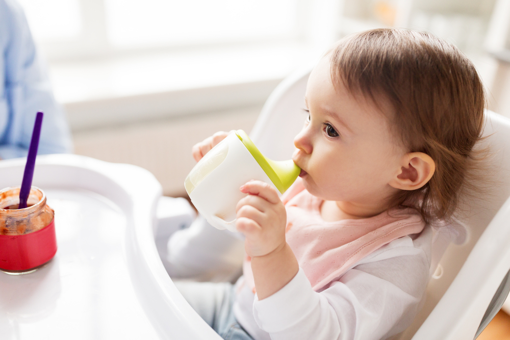 A baby drinking from a standard baby sippy cup A baby drinking from a standard baby sippy cup