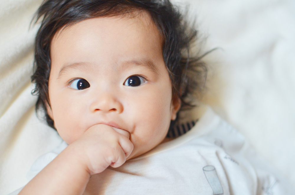 A baby biting their knuckles A baby biting their knuckles