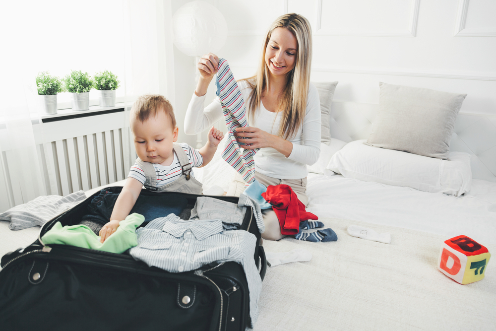 A woman packing useful things she might need when traveling with a baby A woman packing useful things she might need when traveling with a baby