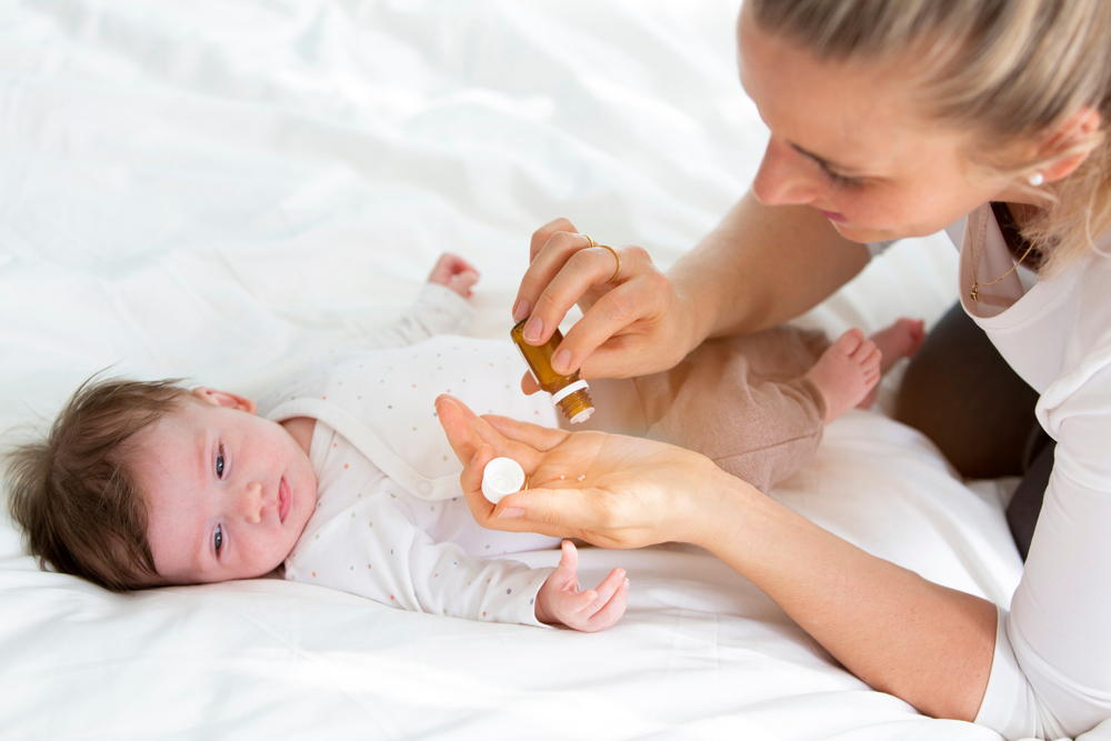 A woman gives her baby medication specifically designed to treat fever from teething in infants A woman gives her baby medication specifically designed to treat fever from teething in infants