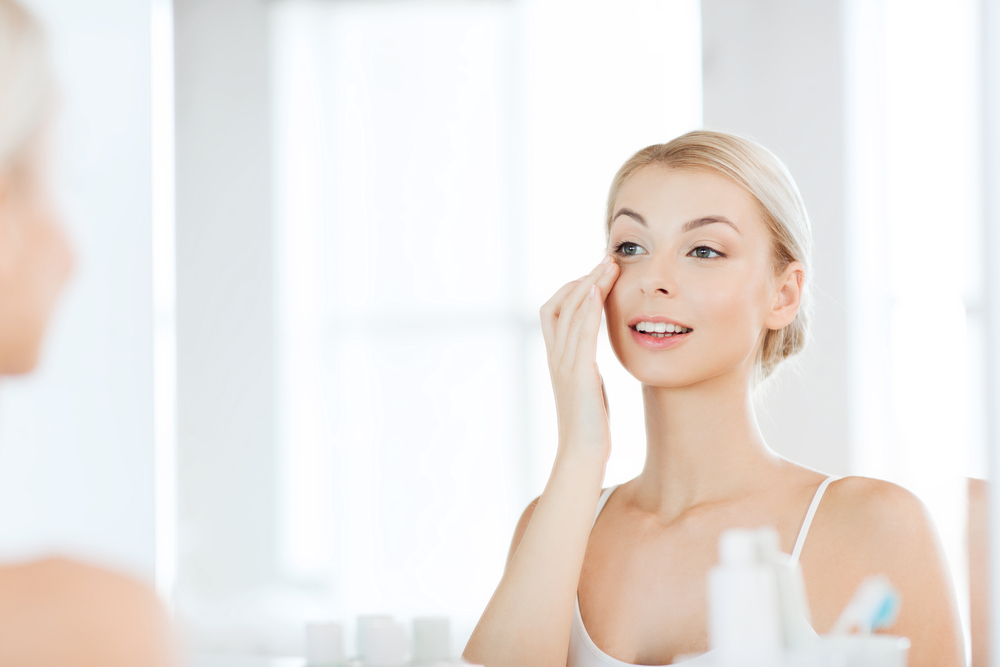 A young woman uses moisturaizer to prevent under-eye wrinkles A young woman uses moisturaizer to prevent under-eye wrinkles