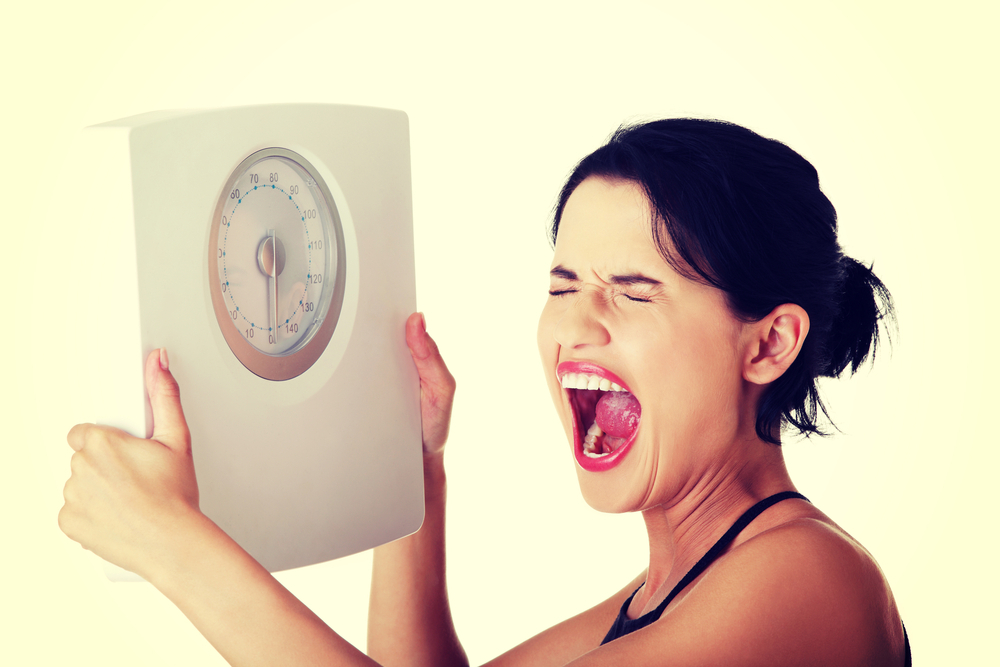 Frustrated young woman with scale