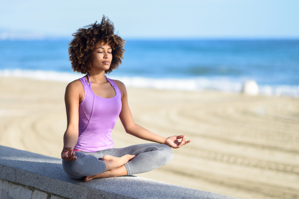 woman doing yoga asana on the beach with closed eyes to manage stress woman doing yoga asana on the beach with closed eyes to manage stress