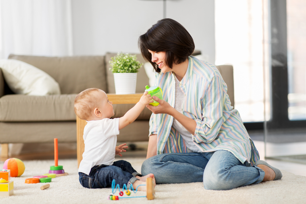 A woman giving her baby a drink after weaning the baby off formula A woman giving her baby a drink after weaning the baby off formula