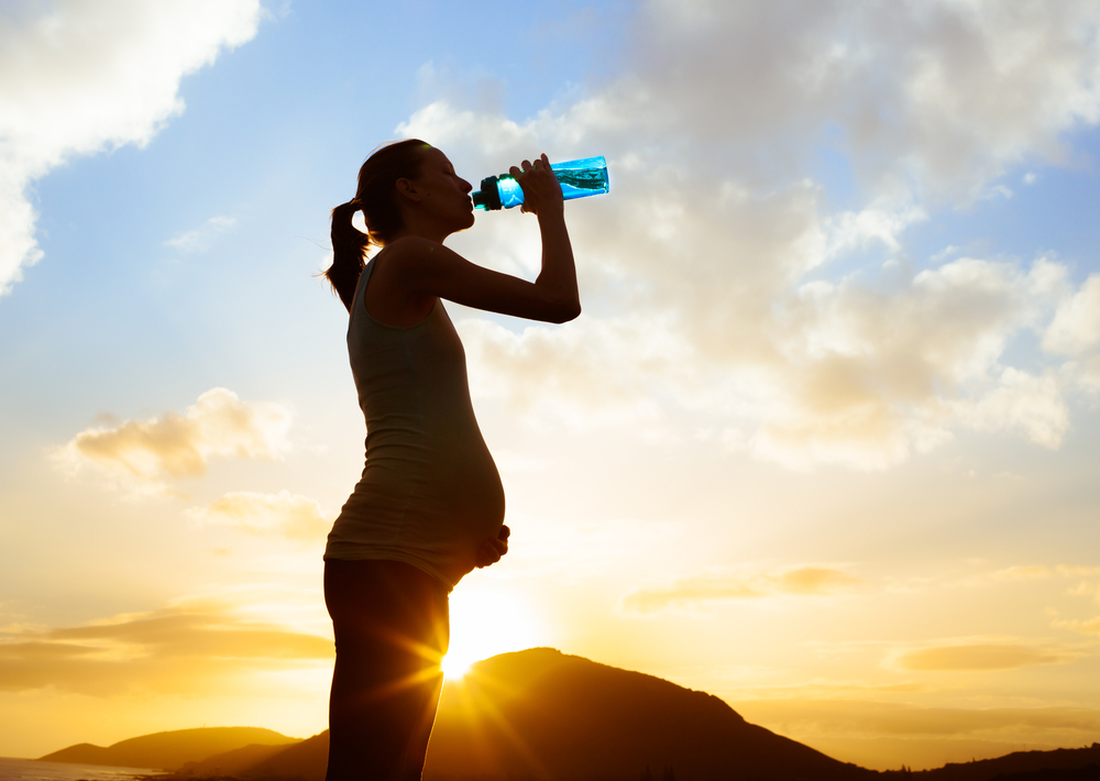 A pregnant woman drinking water A pregnant woman drinking water