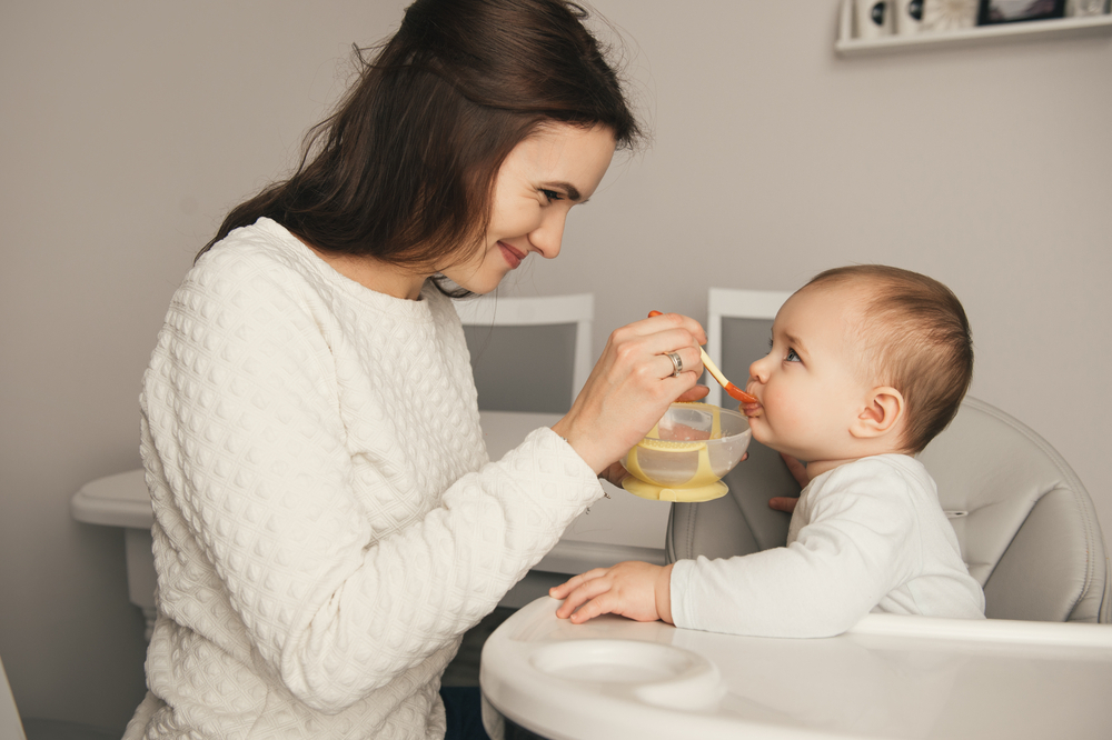 A mother is feeding her baby according to the 8-month-old’s meal plan A mother is feeding her baby according to the 8-month-old’s meal plan