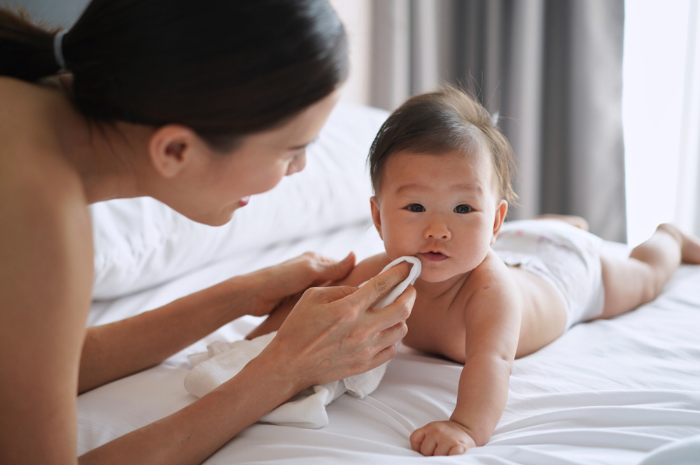 A woman gently dries her your newborn’s face to prevent milia A woman gently dries her your newborn’s face to prevent milia