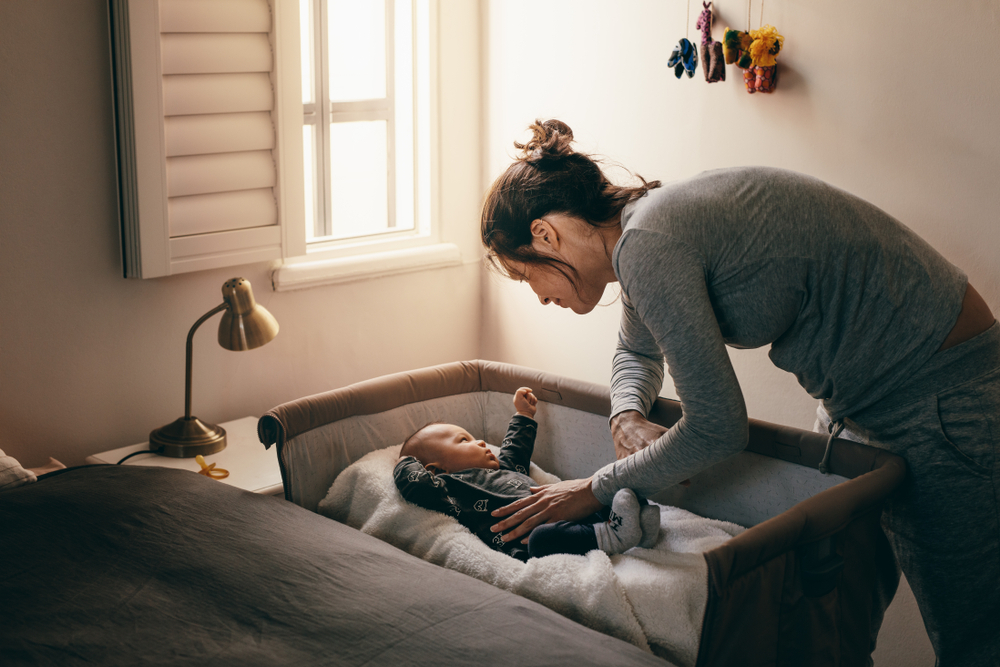A woman trying to get her baby to sleep on their back A woman trying to get her baby to sleep on their back