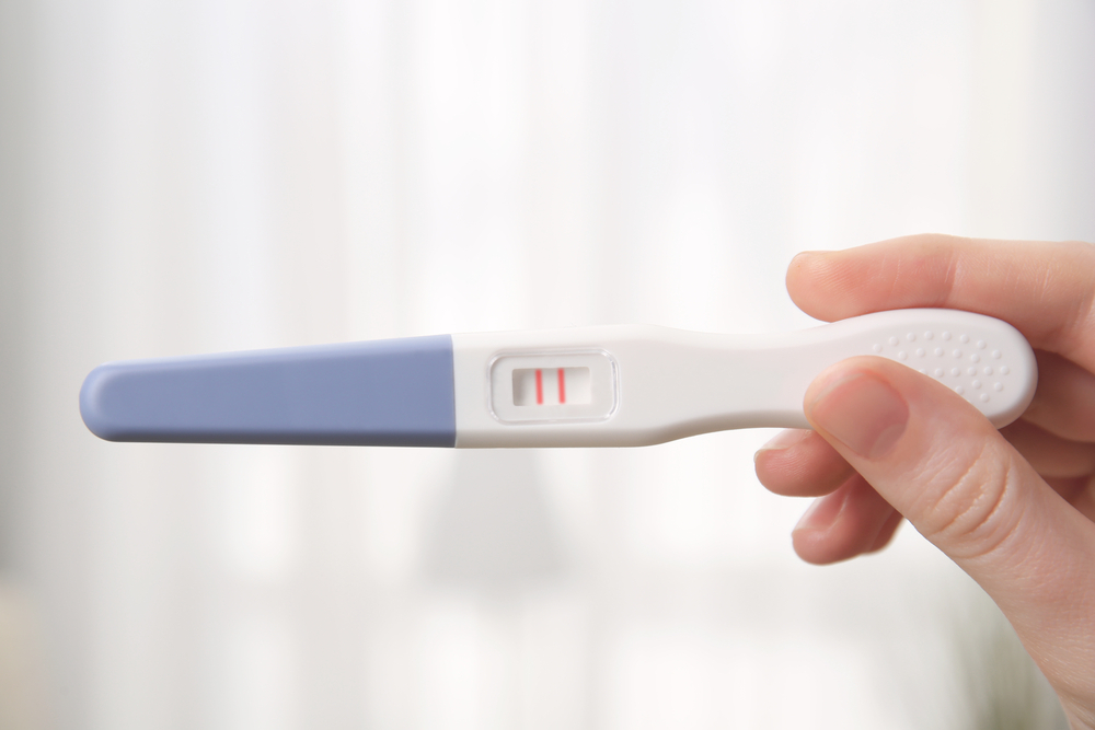 woman holding a positive pregnancy test woman holding a positive pregnancy test
