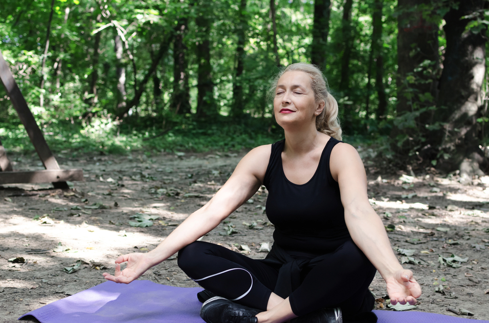 A woman is practicing yoga to treat headaches during menopause A woman is practicing yoga to treat headaches during menopause