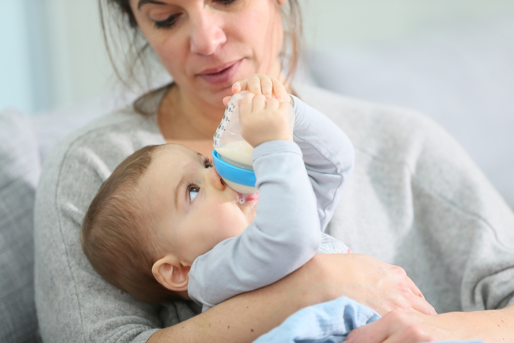 A woman feeds her baby according to a sample feeding schedule for formula-fed babies A woman feeds her baby according to a sample feeding schedule for formula-fed babies